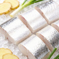 Raw hairtail segments stacked on ice with ginger slices and spring onion