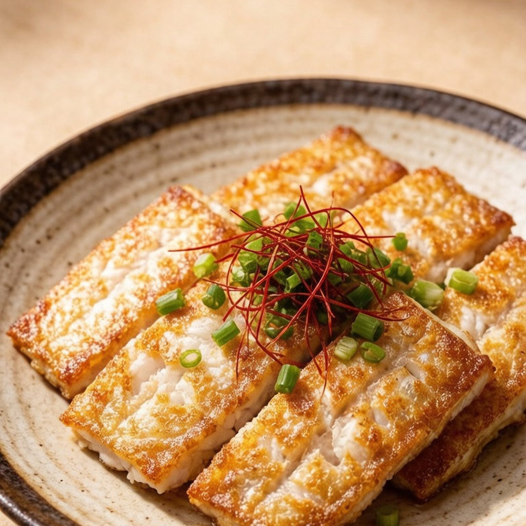Pan-fried hairtail segments finished with fine chili threads on a speckled plate
